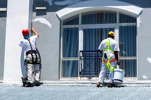 Two painters on harnesses refreshing a storefront near the Redondo Beach pier